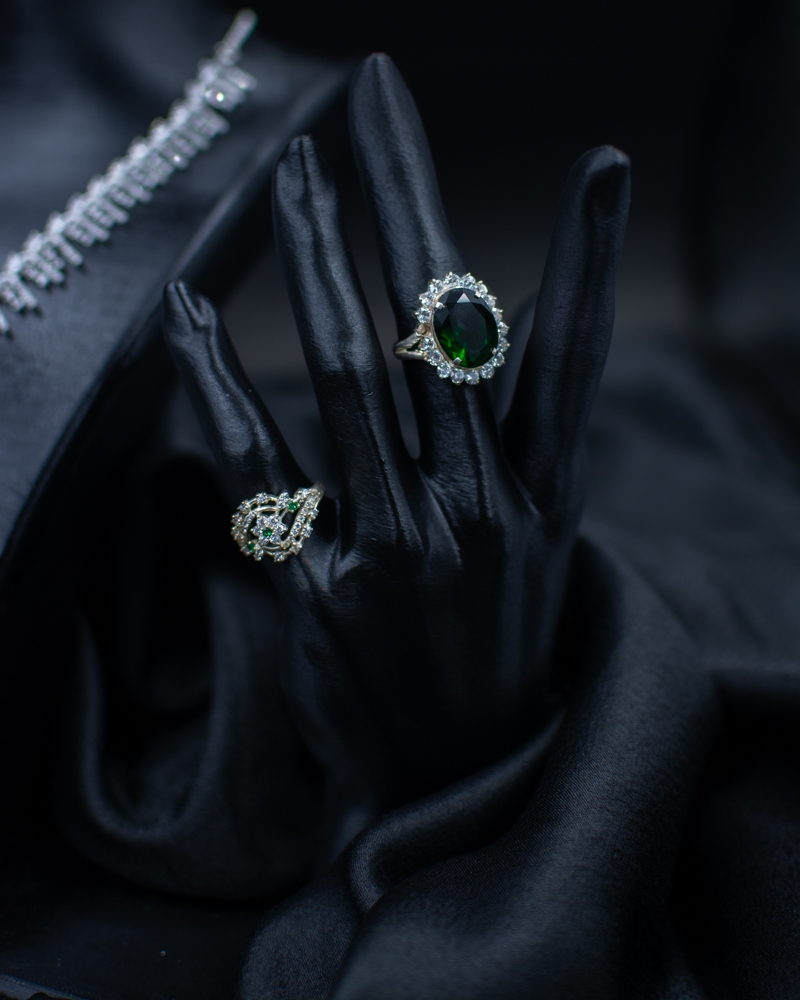 Green Set rings with green stones on black hand display