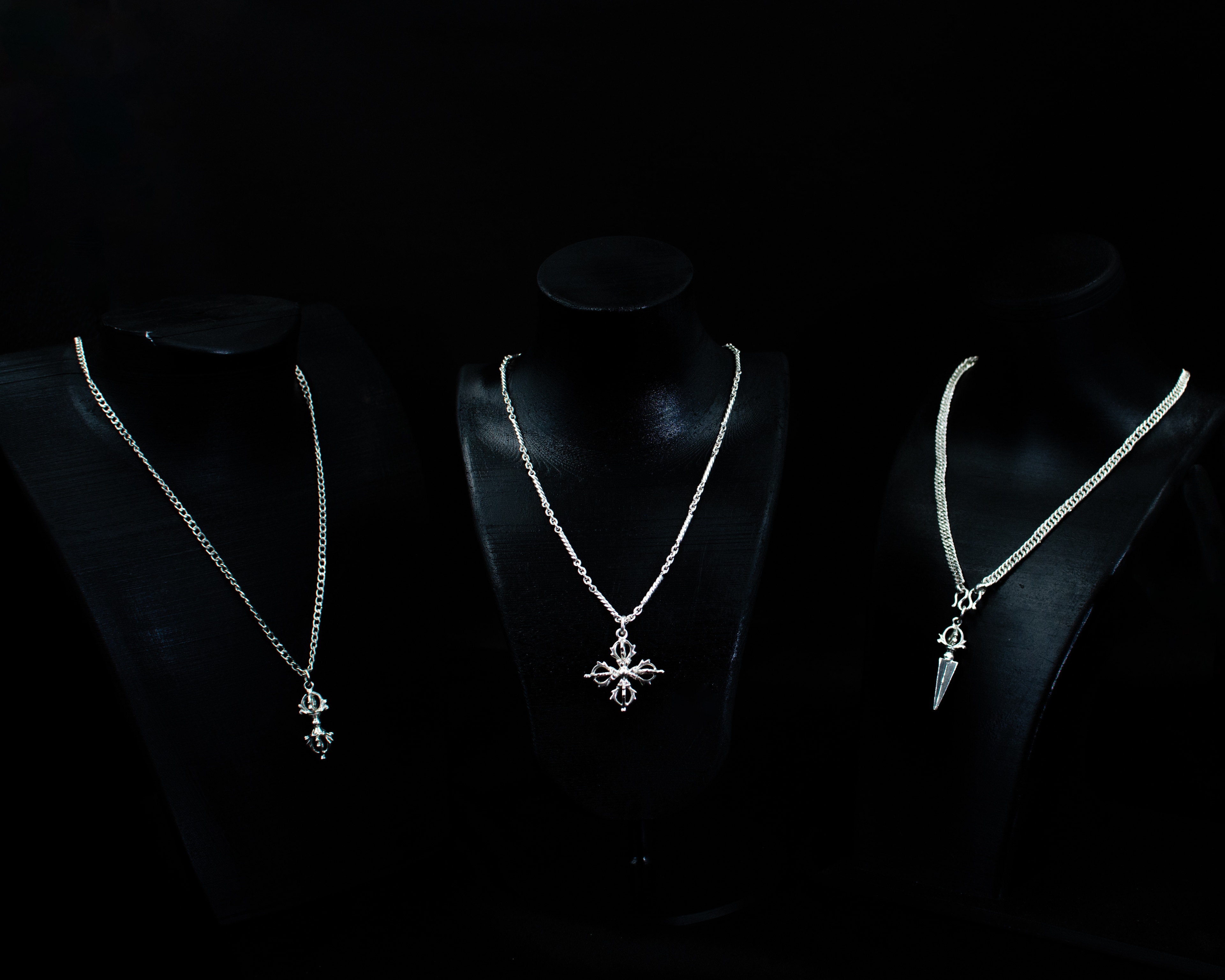 Silver pendant necklaces displayed on black bust stands